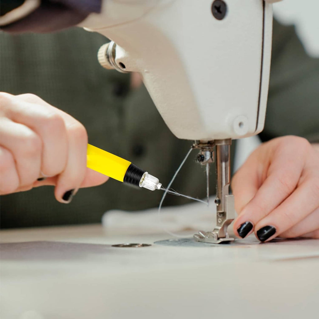 Yellow LED needle threader guiding a needle near a sewing machine