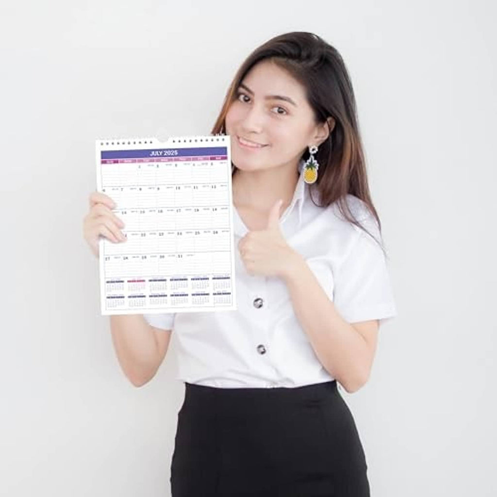 Small 2025 wall calendar held by person, July 2025 month view