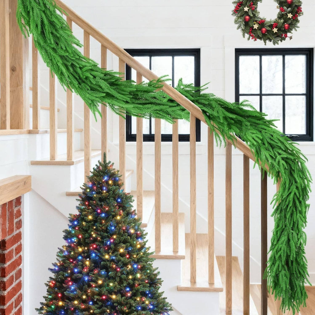Green artificial pine garland draped along a staircase railing with long hanging ends.