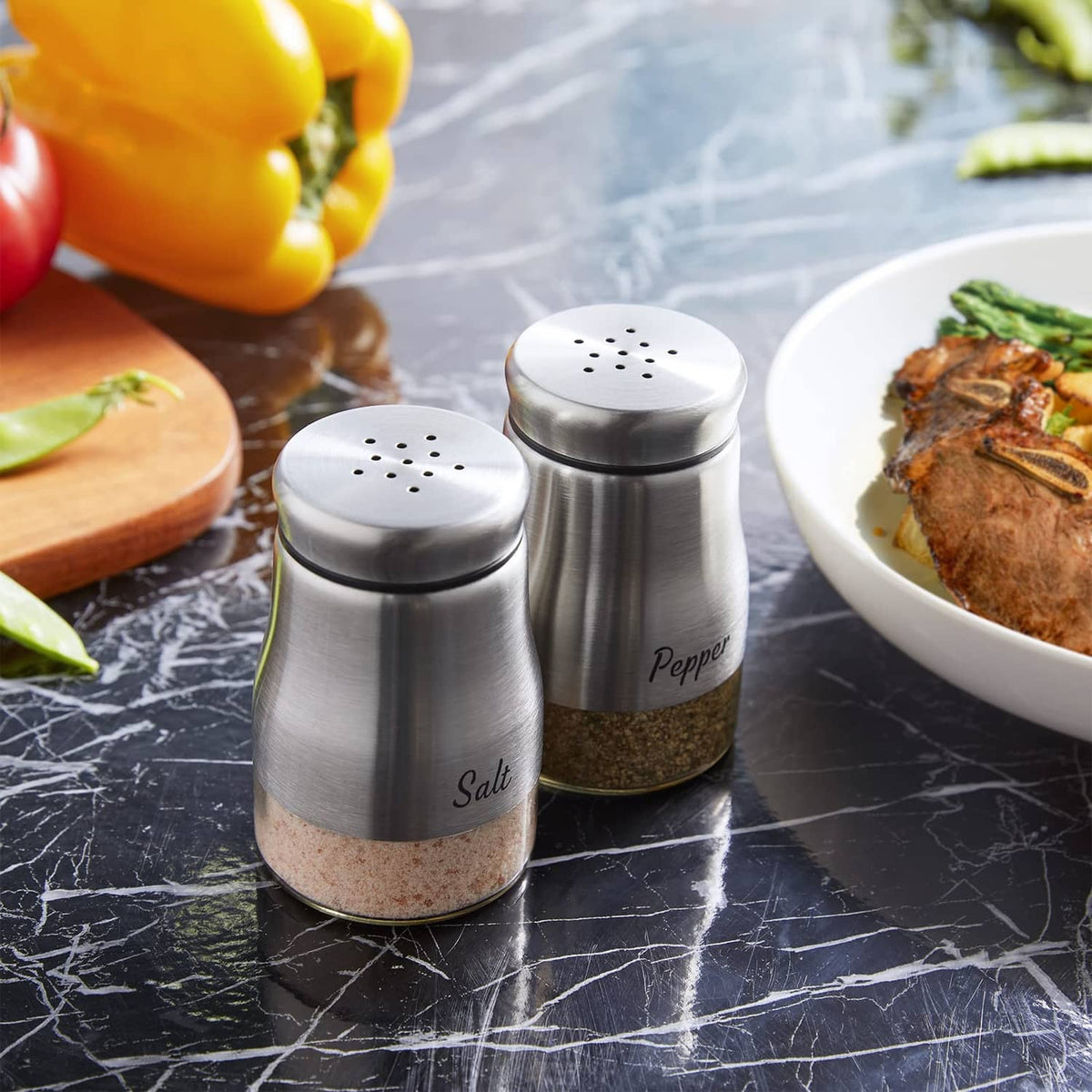 Stainless steel salt and pepper shakers with filled clear bases and 'Salt'/'Pepper' print.