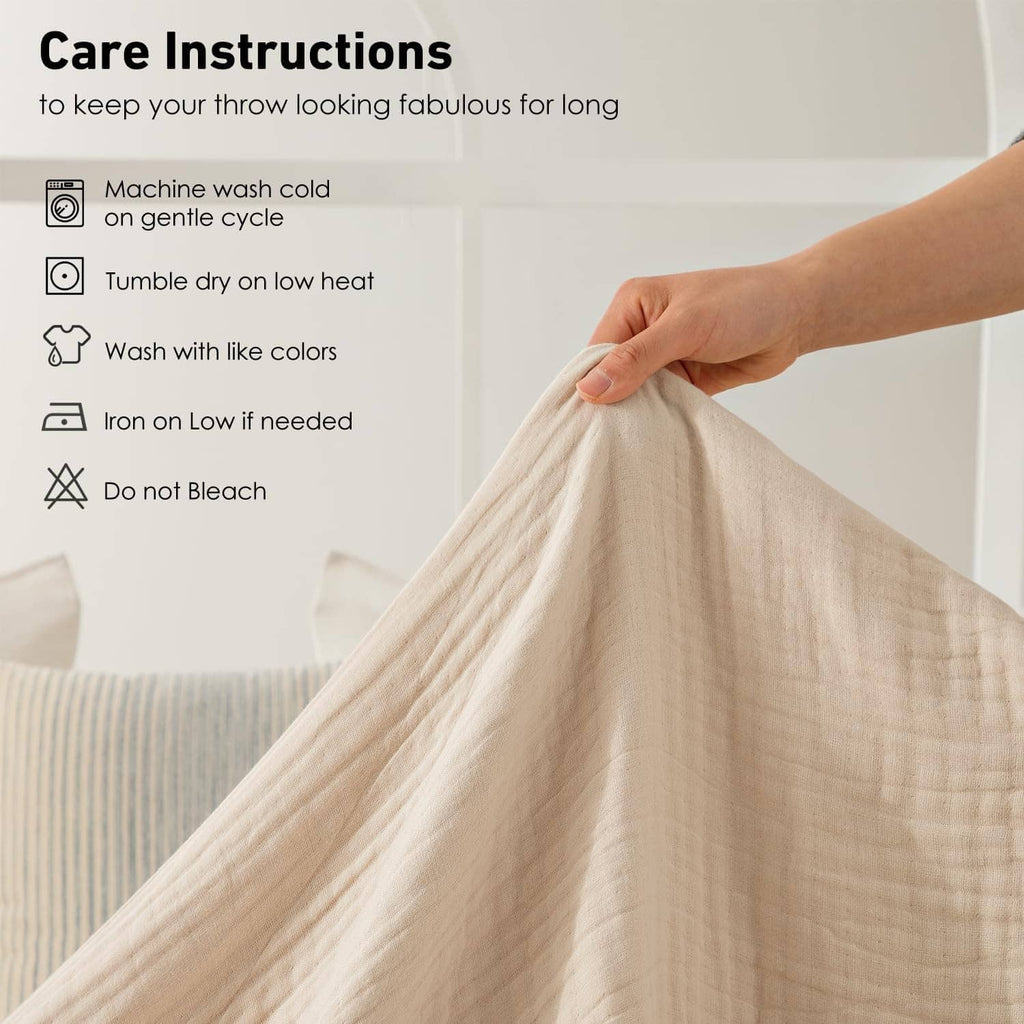 Hand holding a cream muslin blanket corner; gauze weave texture visible.