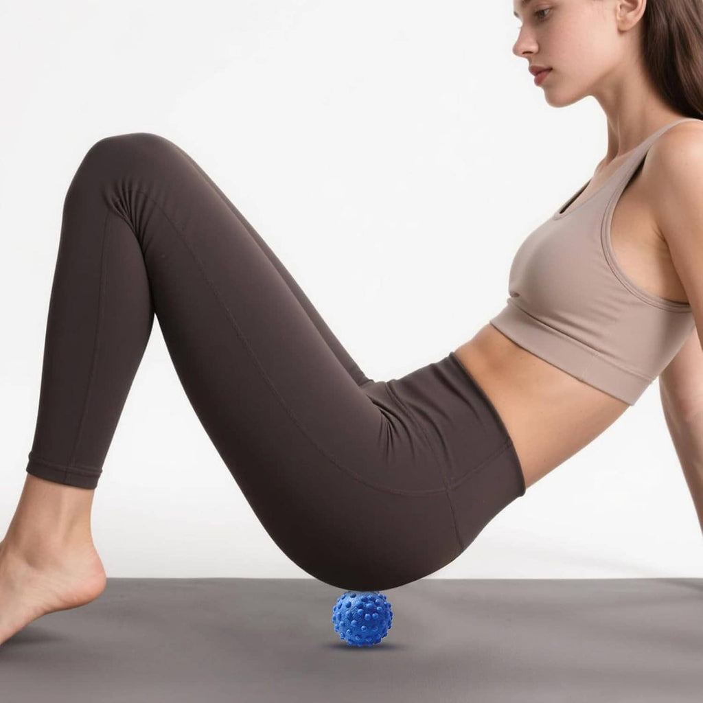 Blue foot massage ball under the sole while stretching with bent legs