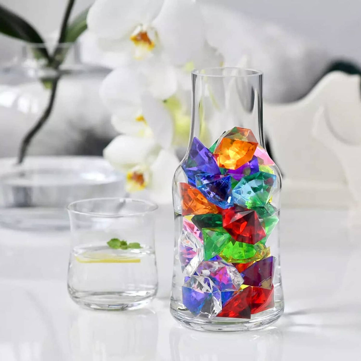 Multicolor faceted acrylic diamond gems inside a clear drinking glass