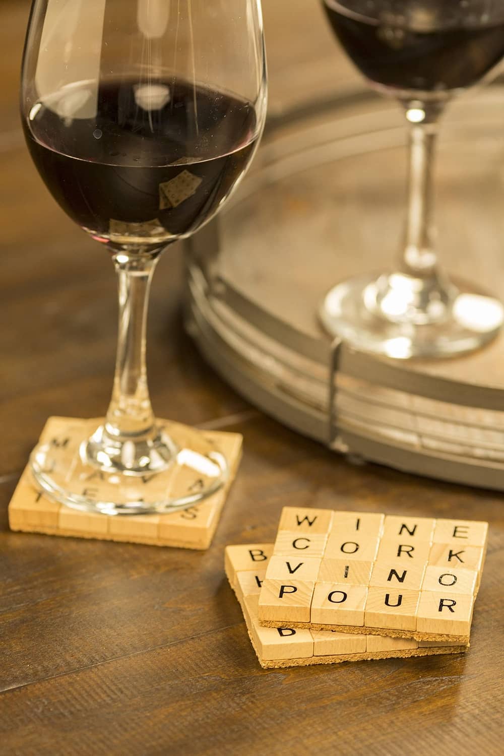 Wine glasses on a wooden table with letter-block coasters