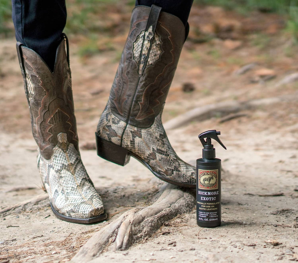 Leather spray cleaner bottle beside patterned cowboy boots on sandy ground
