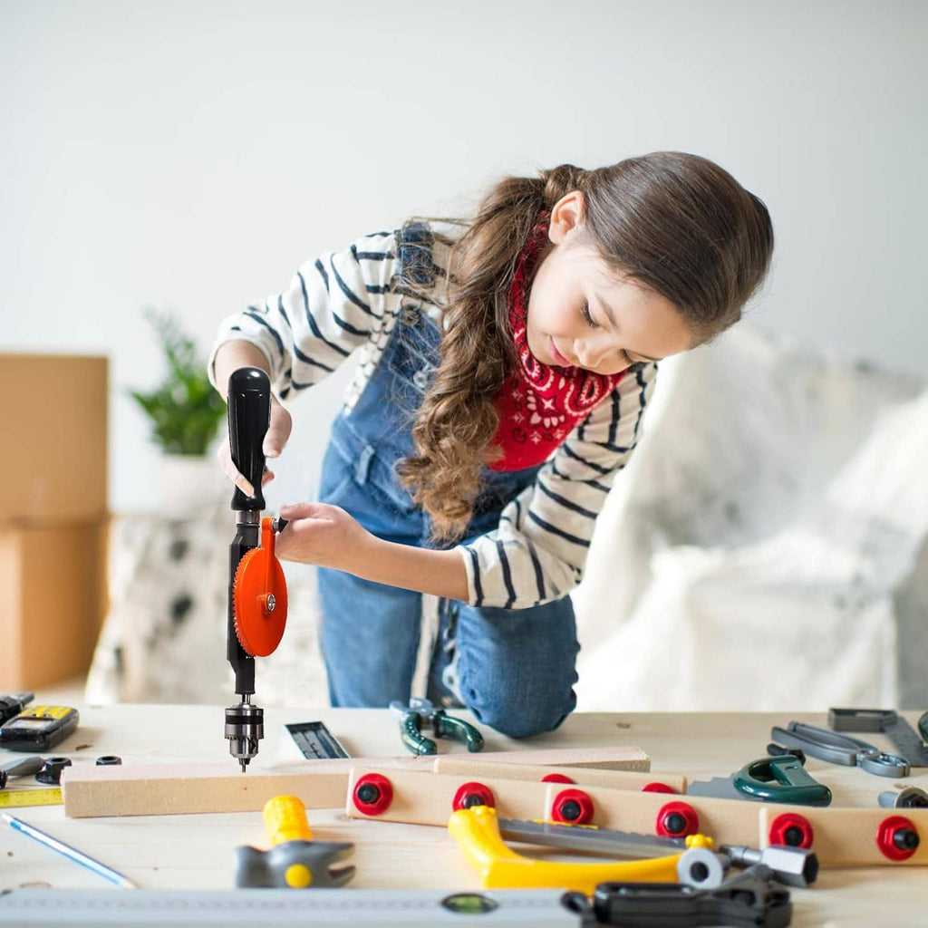 Orange manual hand drill in use, drilling into a wooden board