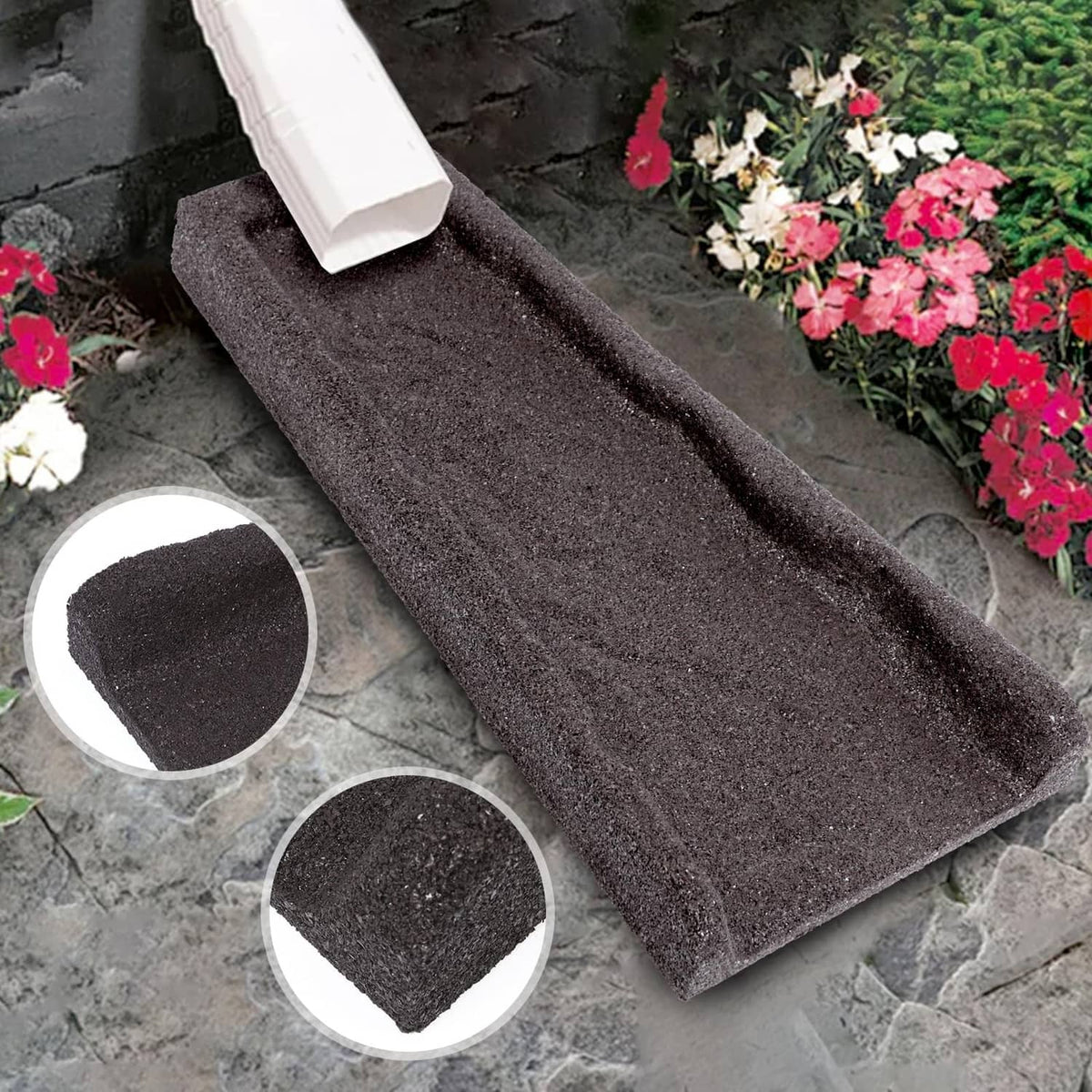 Brown rubber downspout splash block on stone pavers, textured surface visible