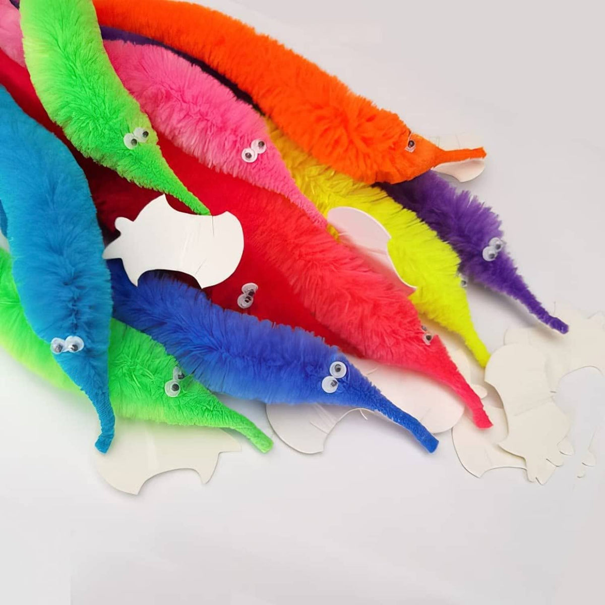 Set of colorful fuzzy worm toys on strings with googly eyes, lying flat