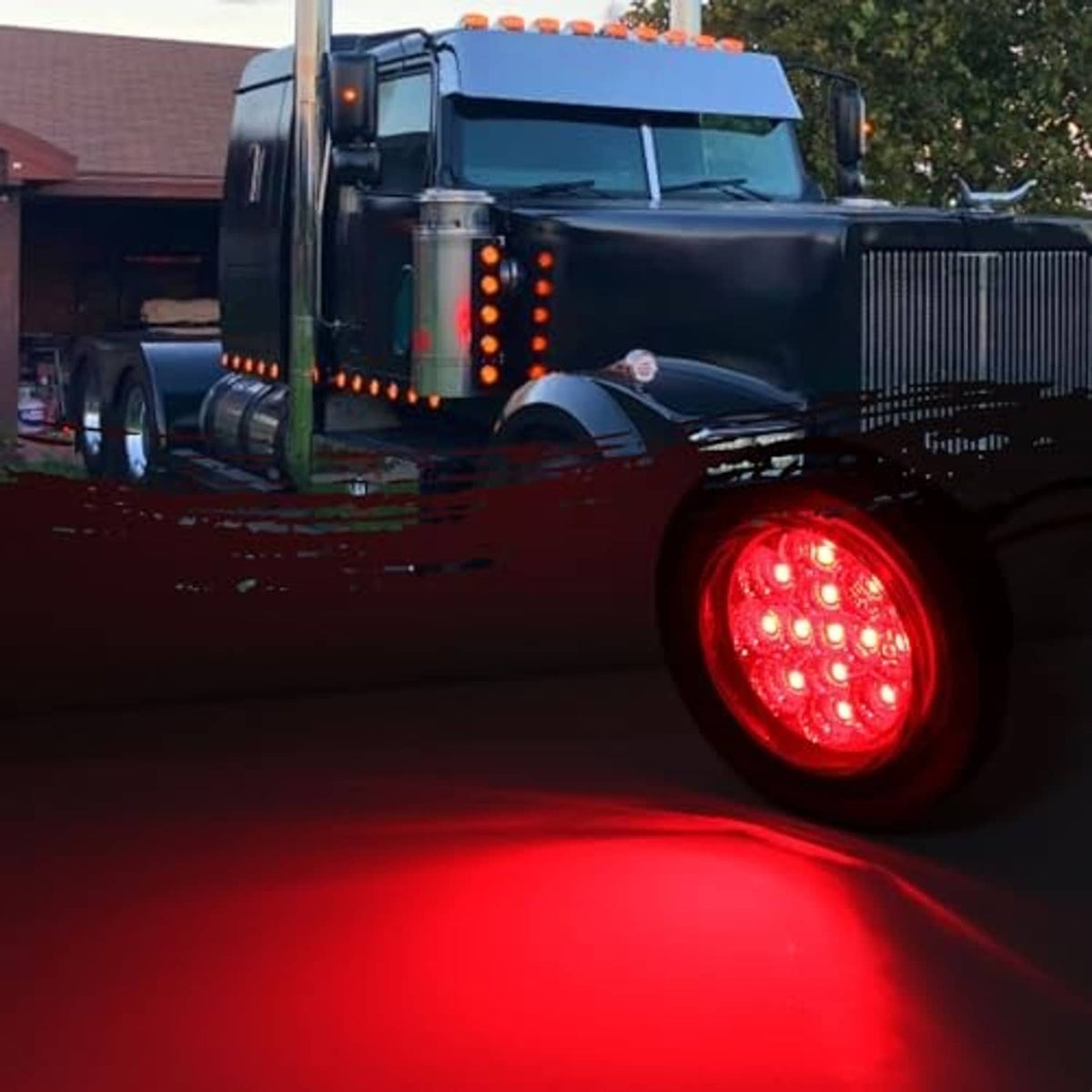 Round red LED side marker light on a truck, glowing red near the front wheel