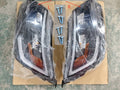 Pair of black headlight assemblies with amber turn signal lenses and LED DRL, boxed