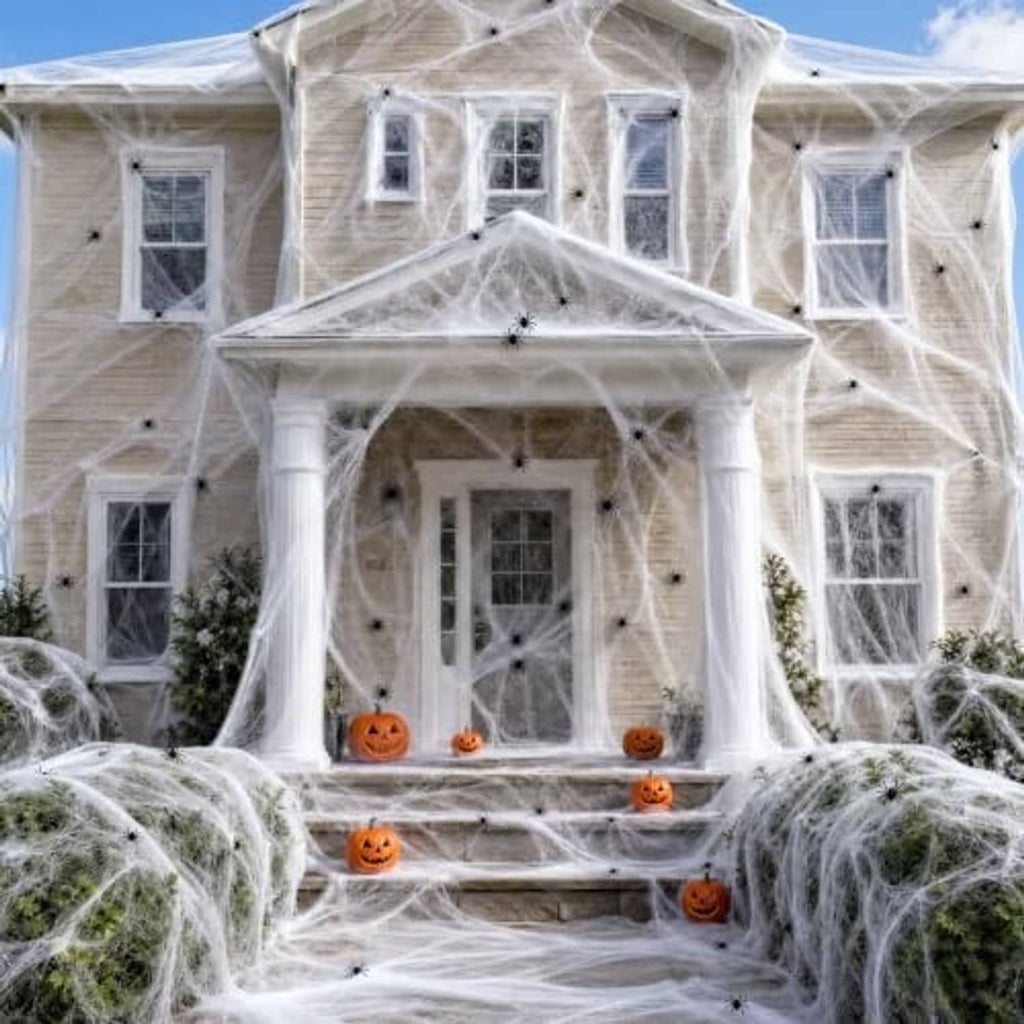 White fabric spider webbing covering a house entrance steps with orange jack-o-lanterns