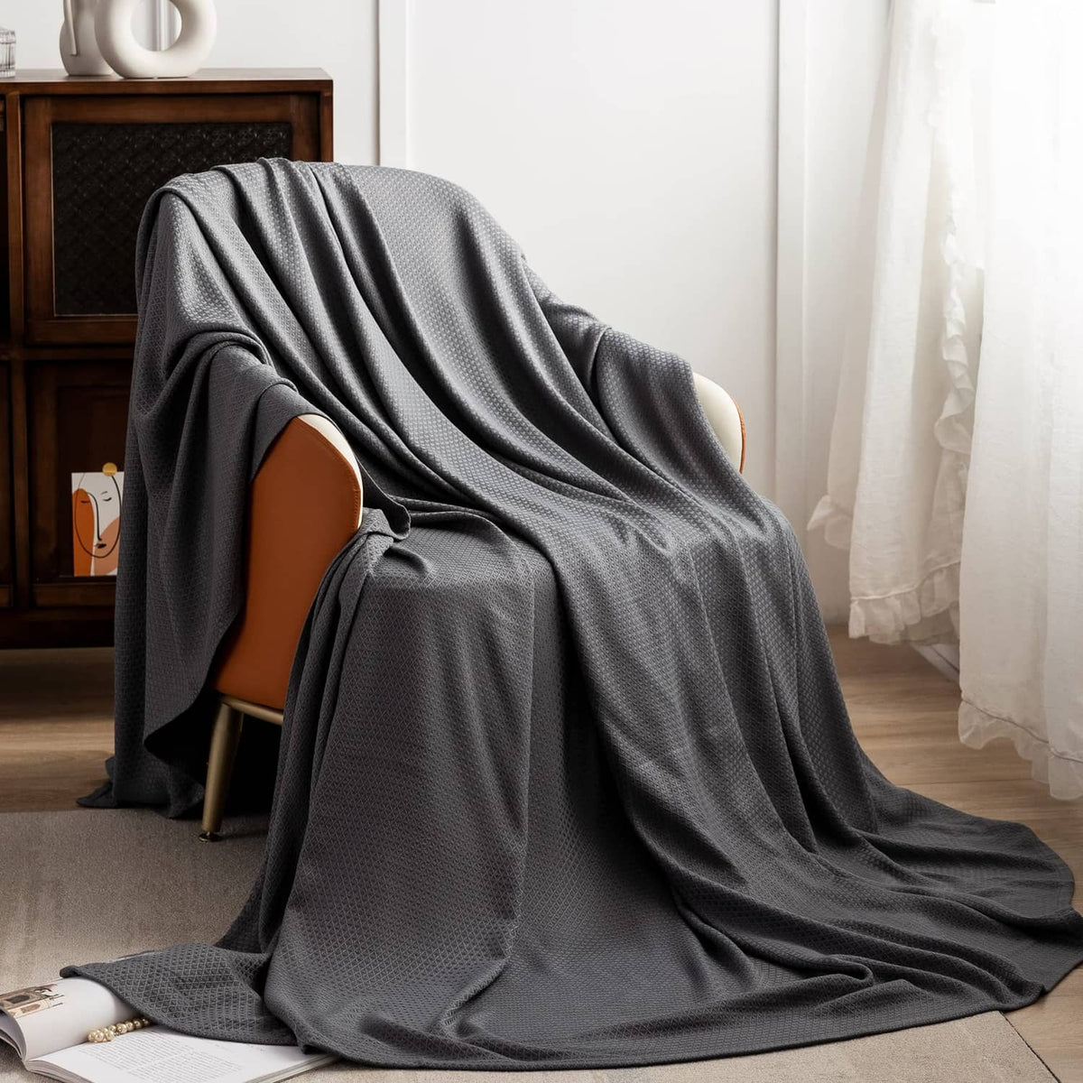Dark gray cooling blanket draped over a chair, smooth woven fabric surface