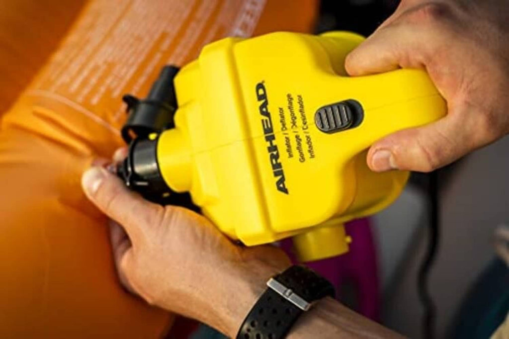 AIRHEAD yellow 12V air pump held in hands with inflation nozzle attachment