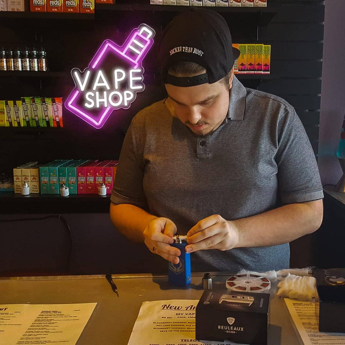 VAPE SHOP neon sign with pink arrow outline and white letters as a person installs it