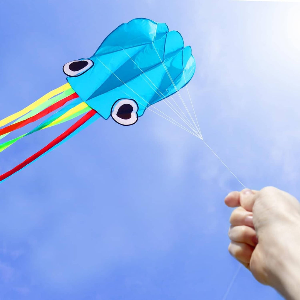 Blue octopus kite with big eye, rainbow ribbons, and string in hand