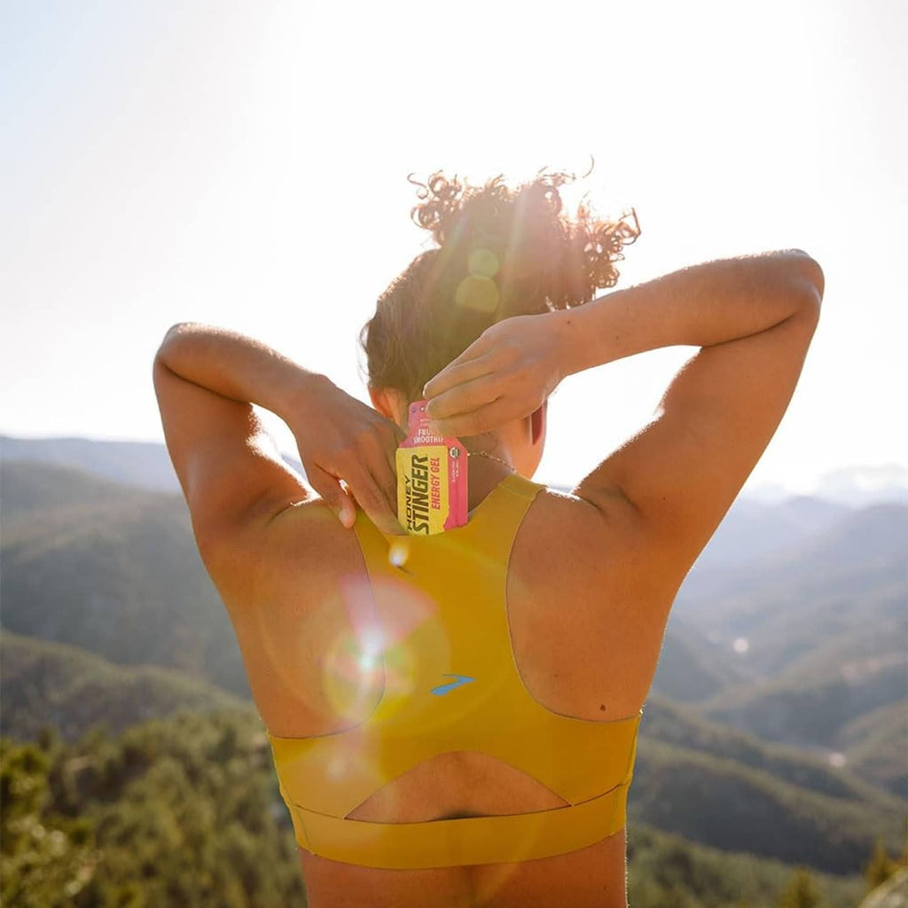 Cyclist holding Honey Stinger energy gel packet near mouth