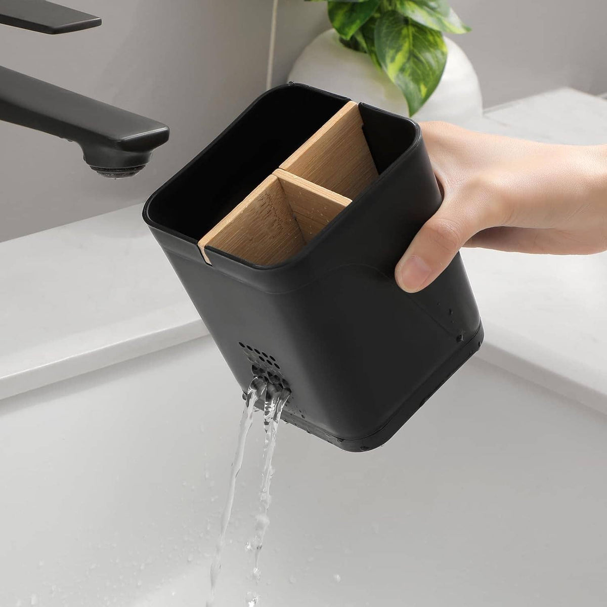 Black toothbrush holder with removable divider, hand holding inner compartments