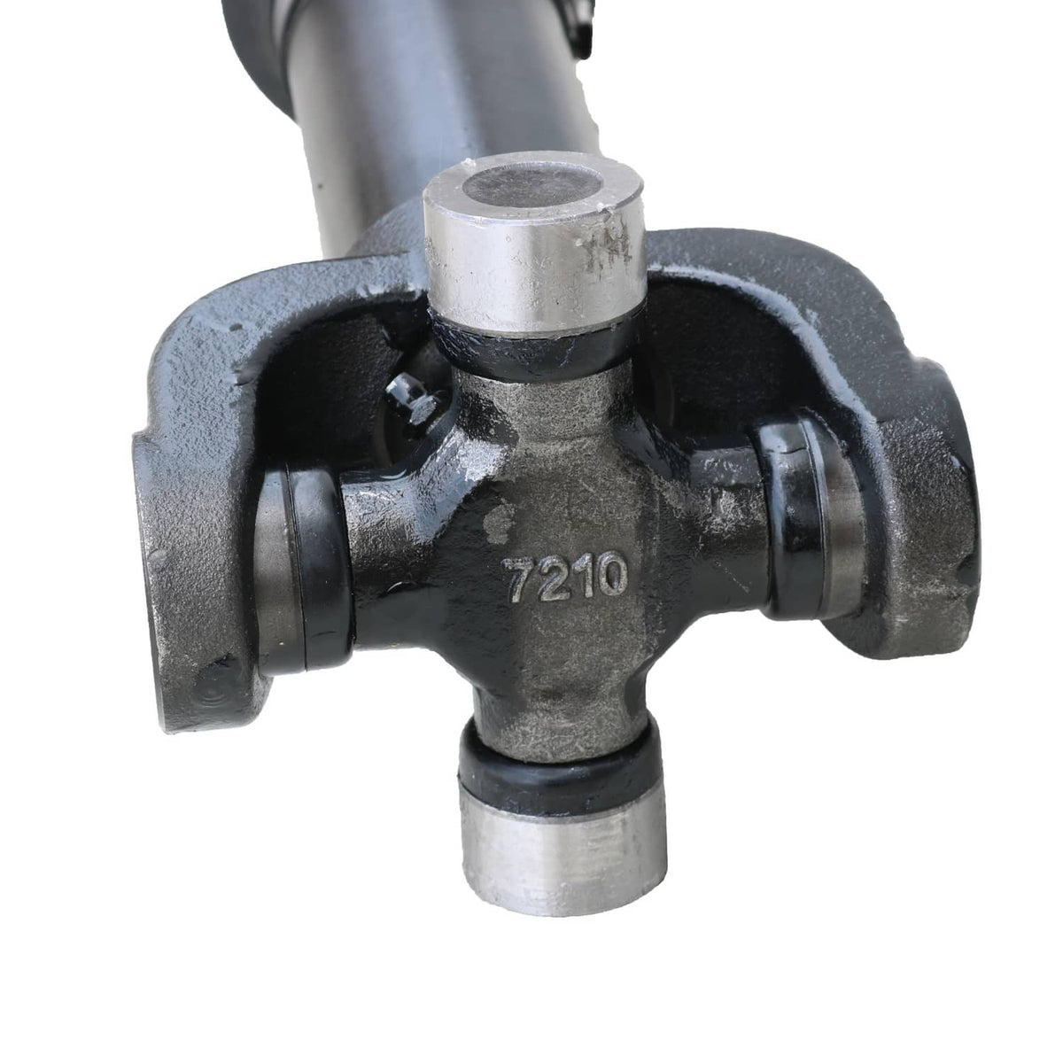 Close-up of rear driveshaft universal joint cross with stamped marking, dark housing