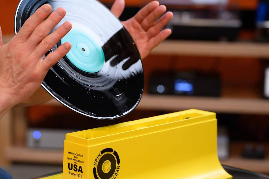 Vinyl record cleaner kit with spinning vinyl disc and yellow storage box