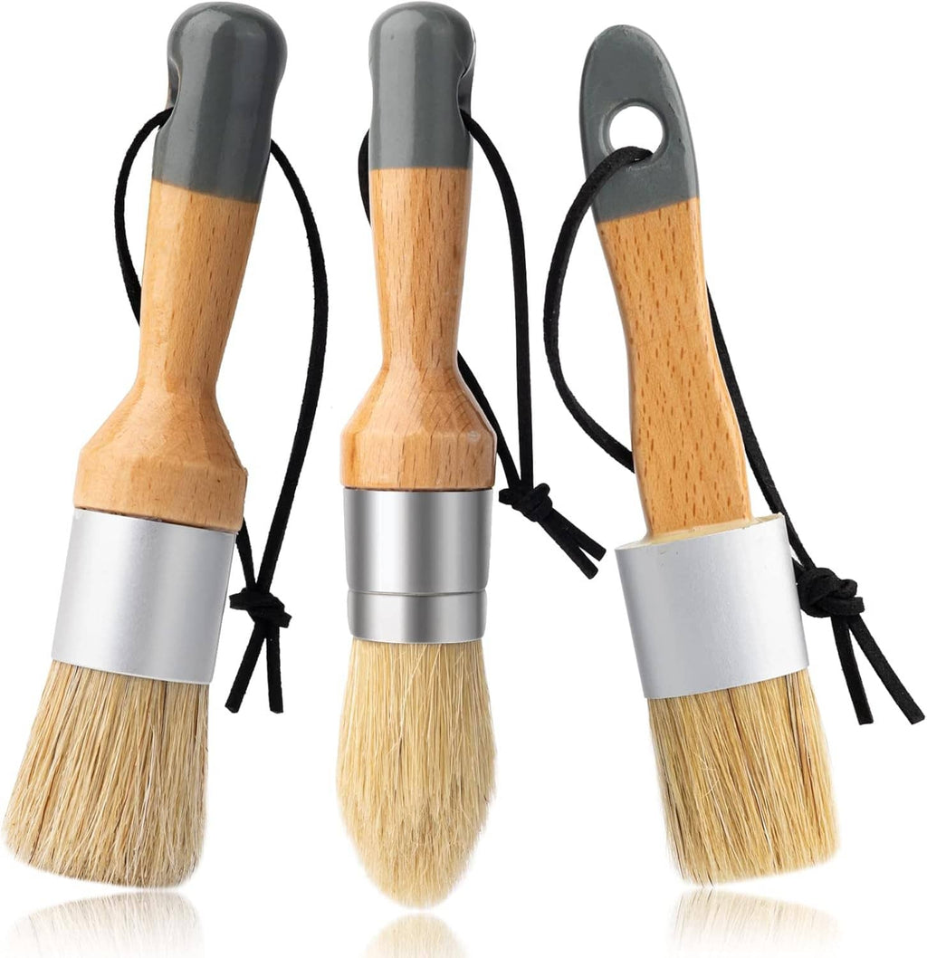 Three small wax paint brushes with light wood handles and beige bristles