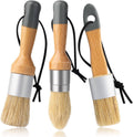 Three small wax paint brushes with light wood handles and beige bristles