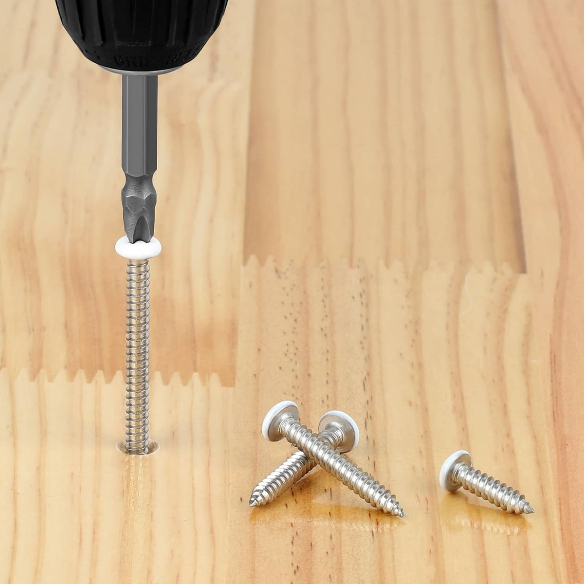 Self tapping screws on light wood with white pan heads and silver threads; drill bit shown.