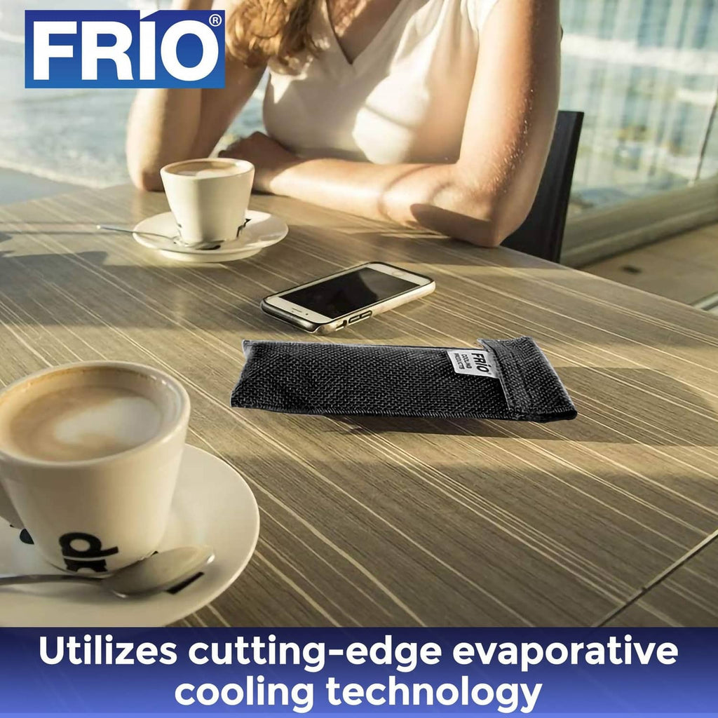 Black FRIO cooling wallet on a table near a phone and coffee cup