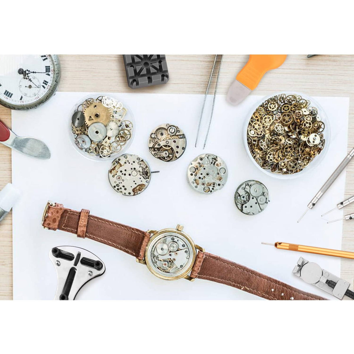 Watch repair kit components on a work surface with tools and watch movement parts