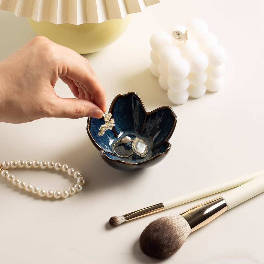 Hand placing a ring into a blue ceramic flower ring holder dish