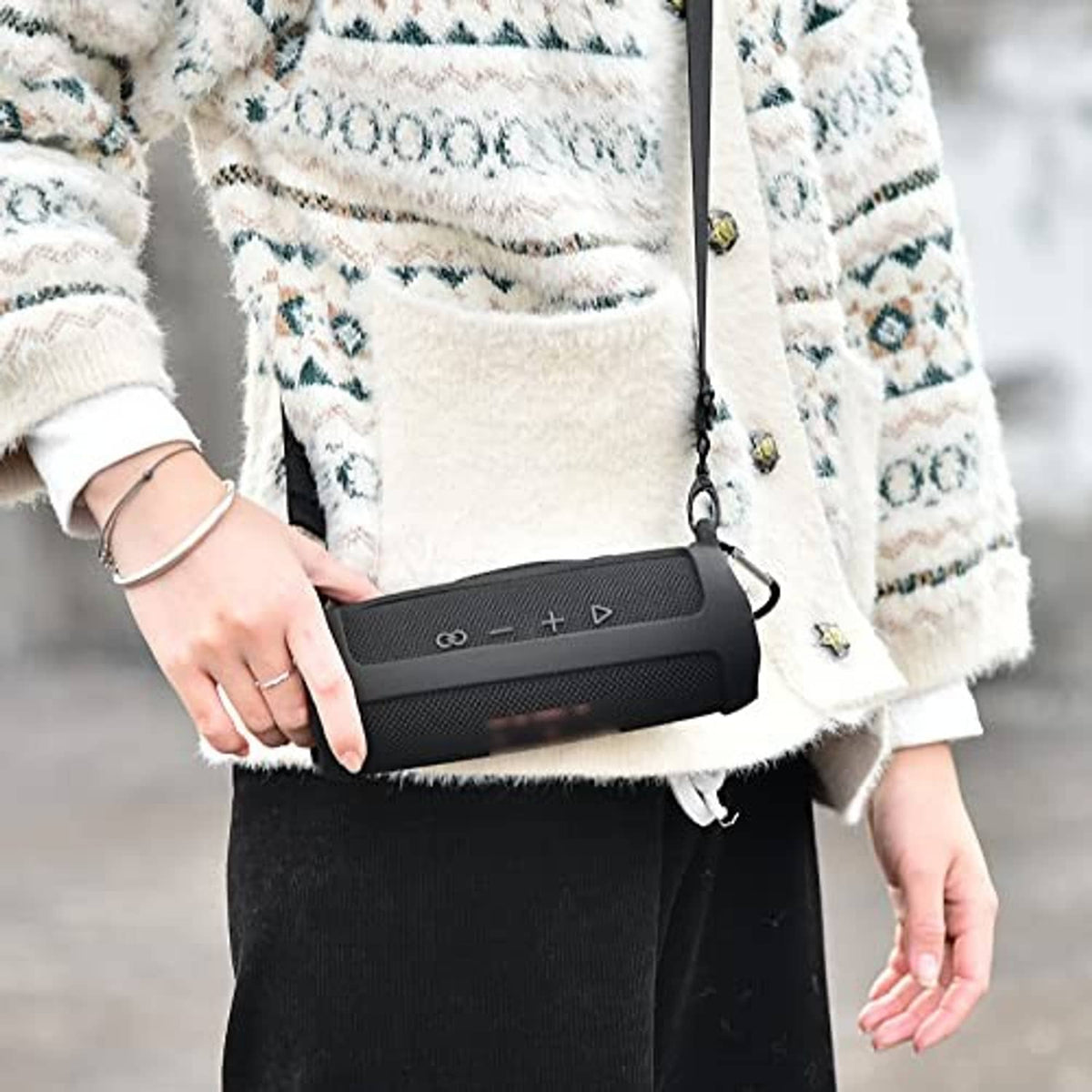 Silicone speaker case worn crossbody with adjustable strap and dark gray mesh.