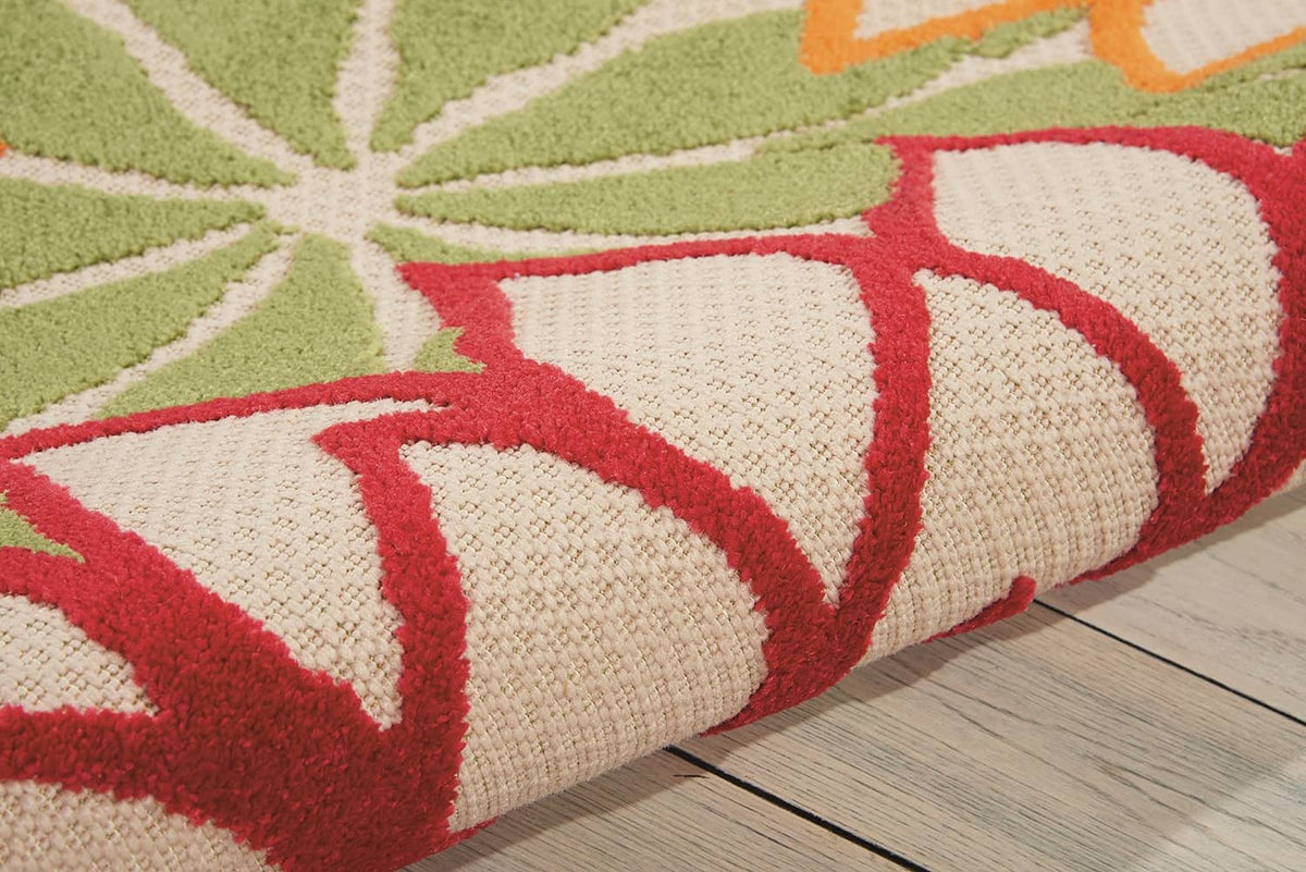 Tropical area rug close-up of red leaf-like shapes and green accents on off-white