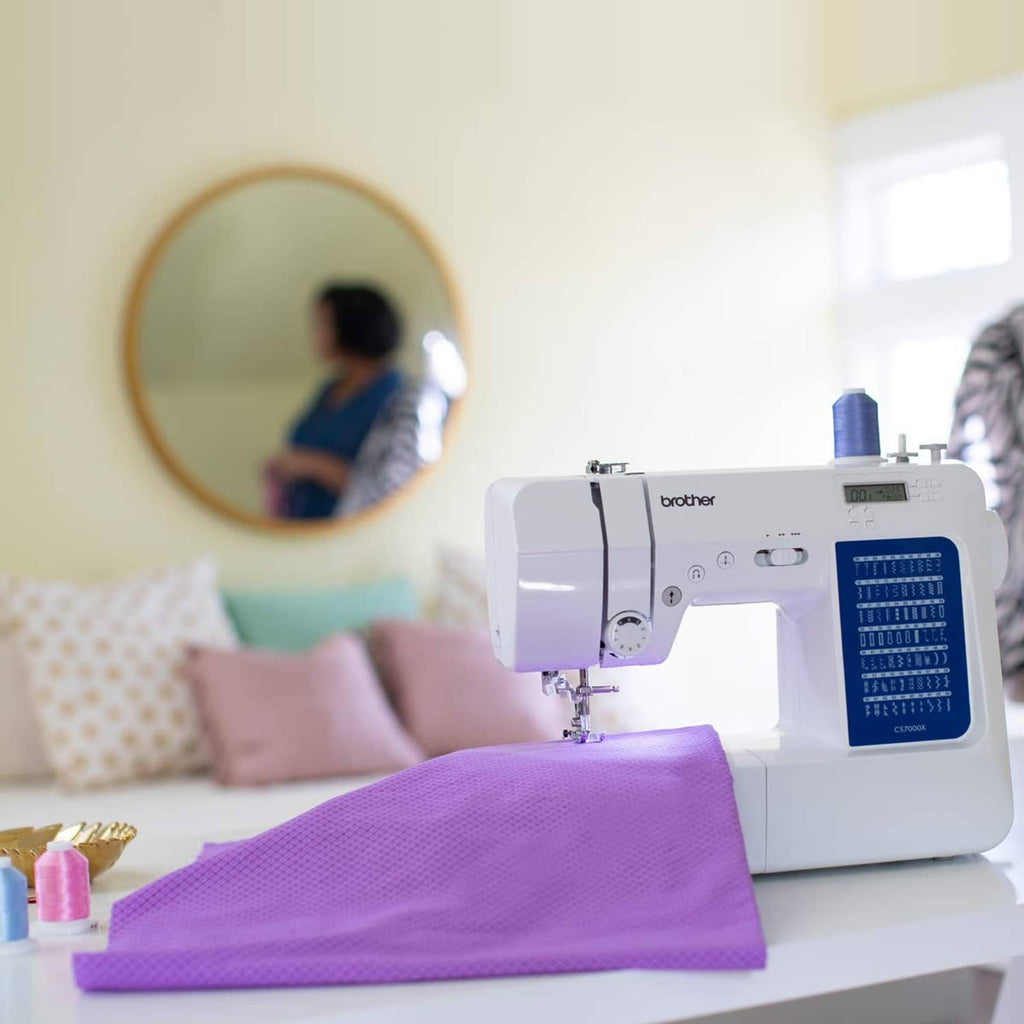 Sewing machine stitching on folded purple fabric with blue stitch panel