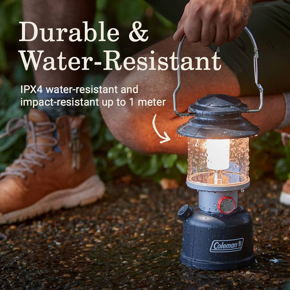 Black Coleman LED lantern with clear housing and red control dial, splashed with water.
