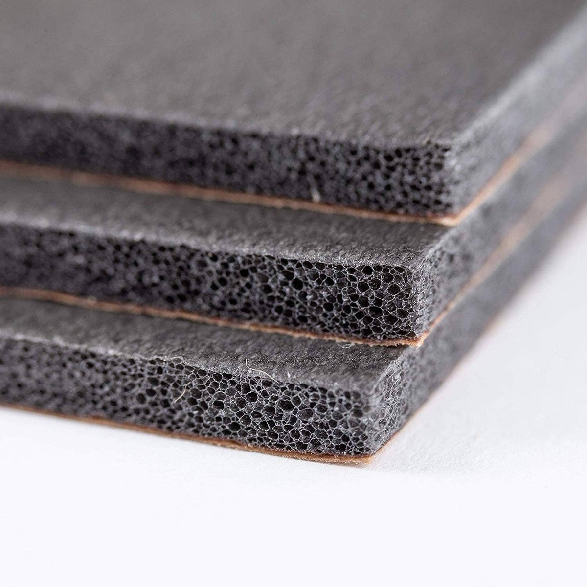 Stacked dark gray sound insulation foam strips with self-adhesive brown backing edge