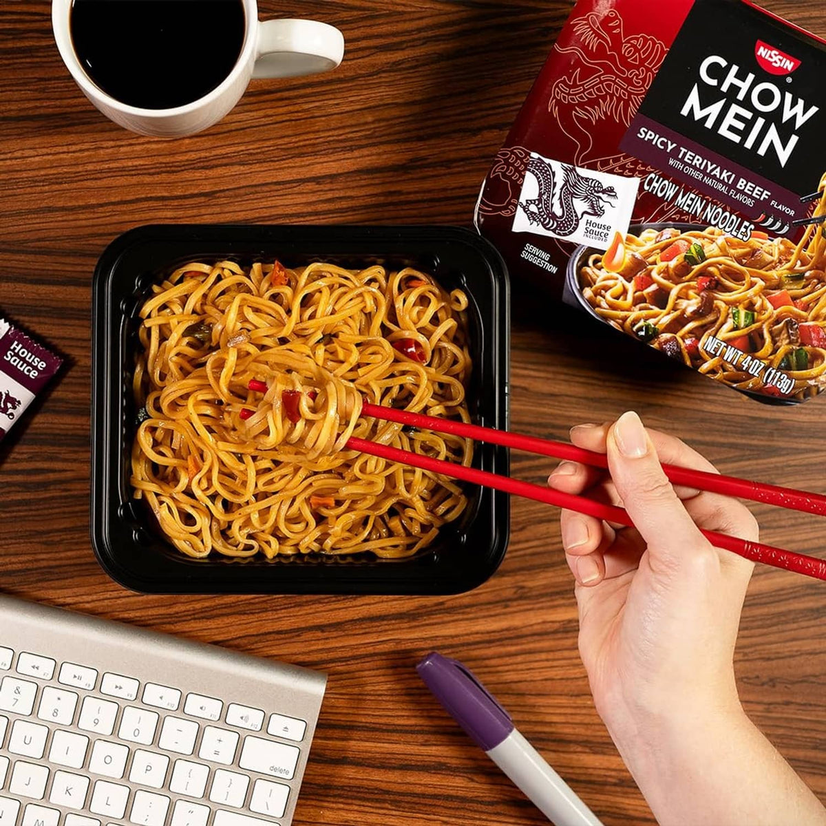Spicy teriyaki beef chow mein noodles in black tray with sauce packet and chopsticks