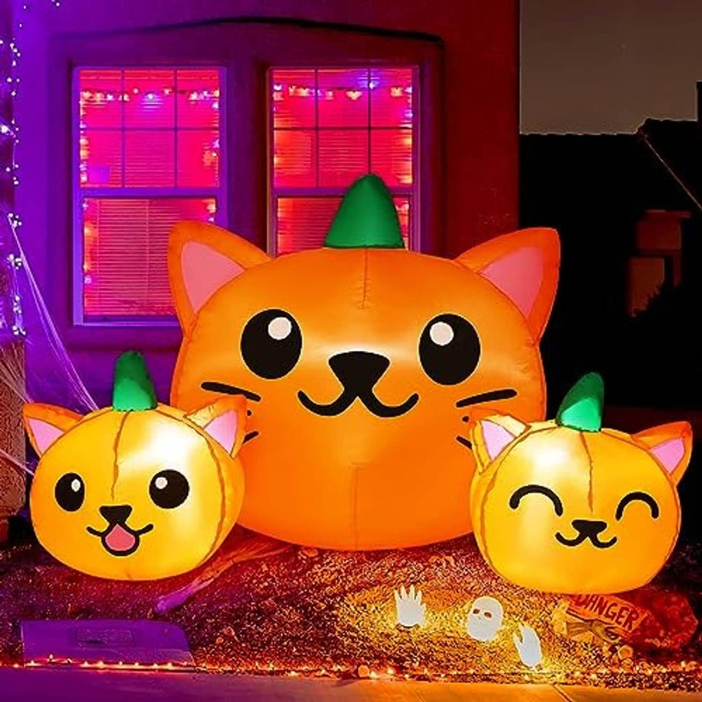 Orange inflatable cat-head trio with green cone hats, glowing outdoor porch decoration