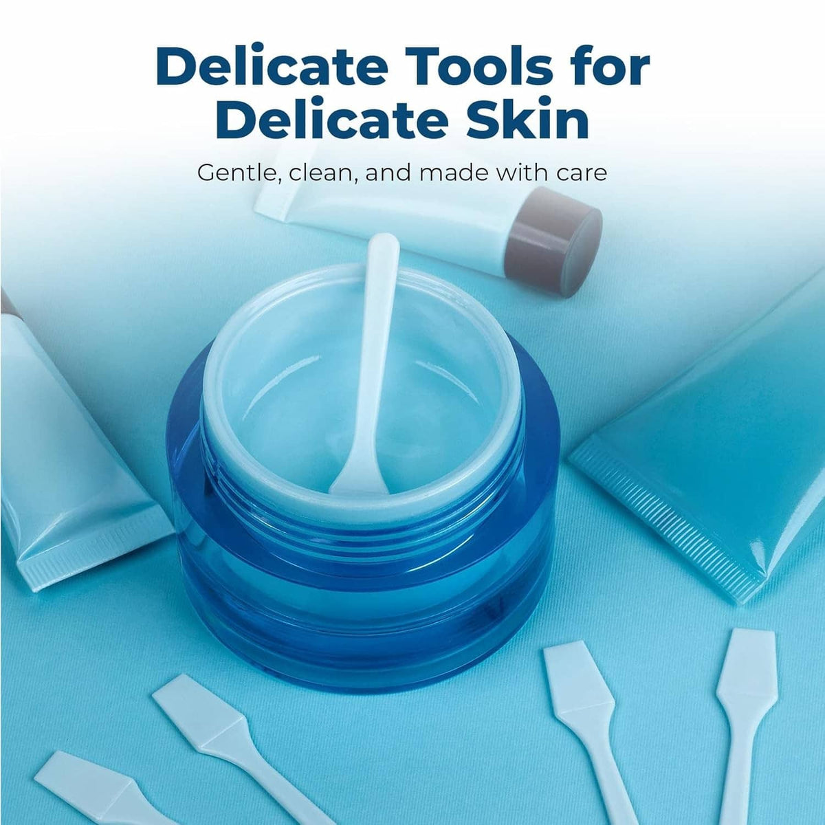 Sky blue mini skincare spatulas with a tube and small jar on a clean surface