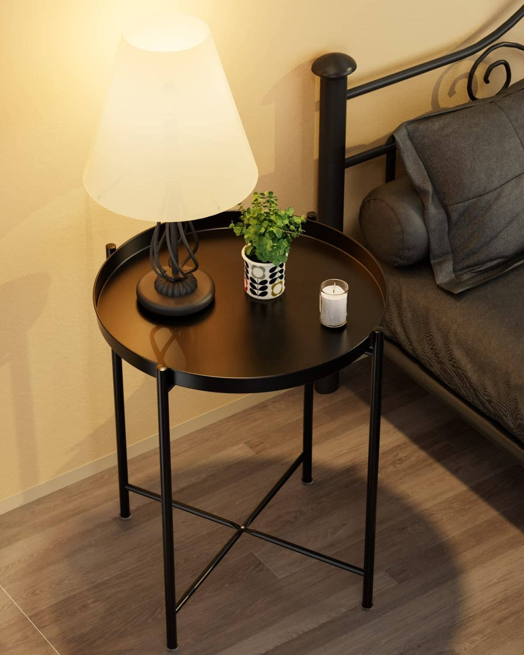 Black metal round side table with open shelf, supporting lamp and decor items