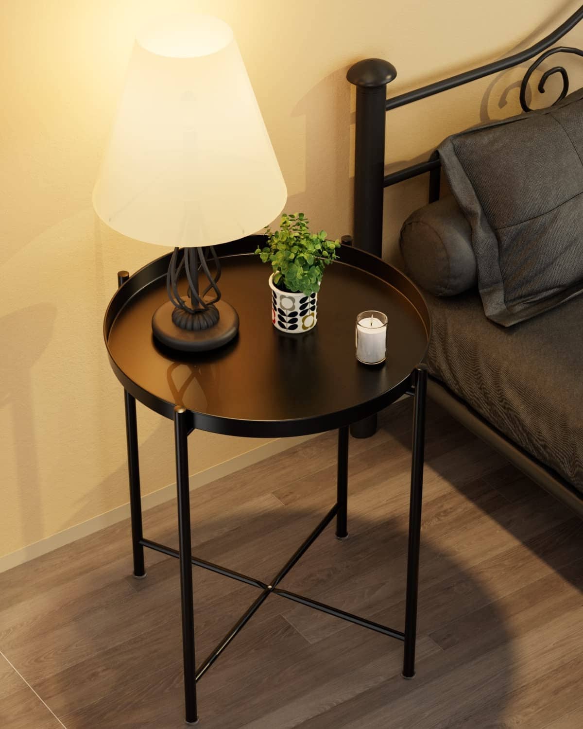 Black metal round side table with open shelf, supporting lamp and decor items