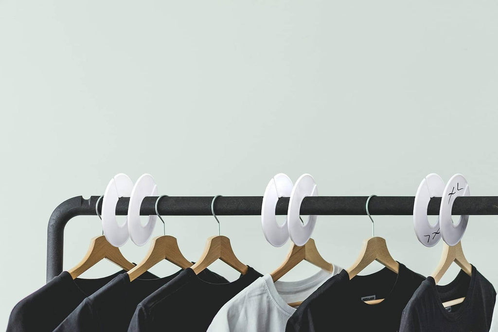 White round clothing rack dividers attached to black rod with hanging shirts