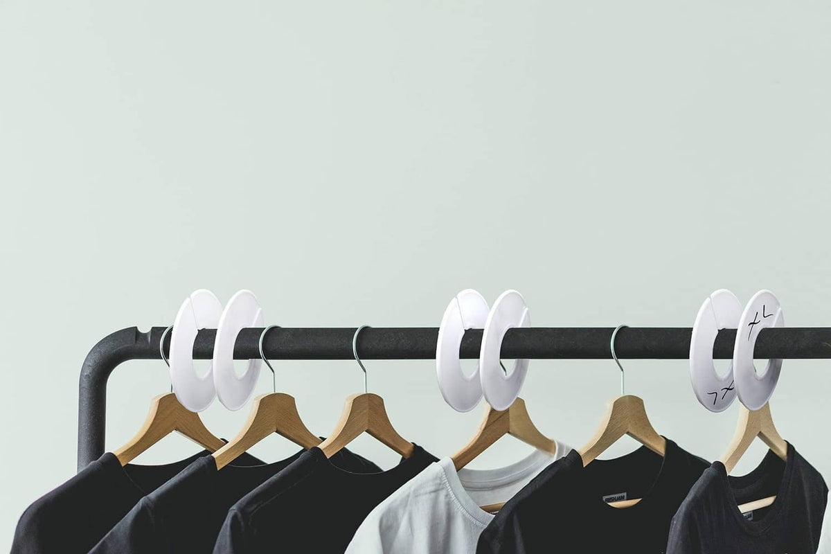 White round clothing rack dividers attached to black rod with hanging shirts