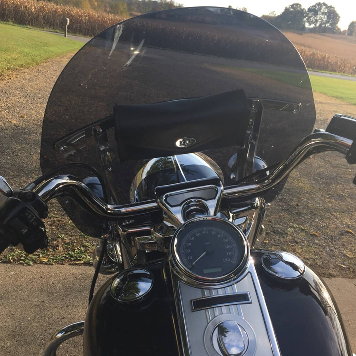 Smoked touring motorcycle windshield with chrome supports on black bike
