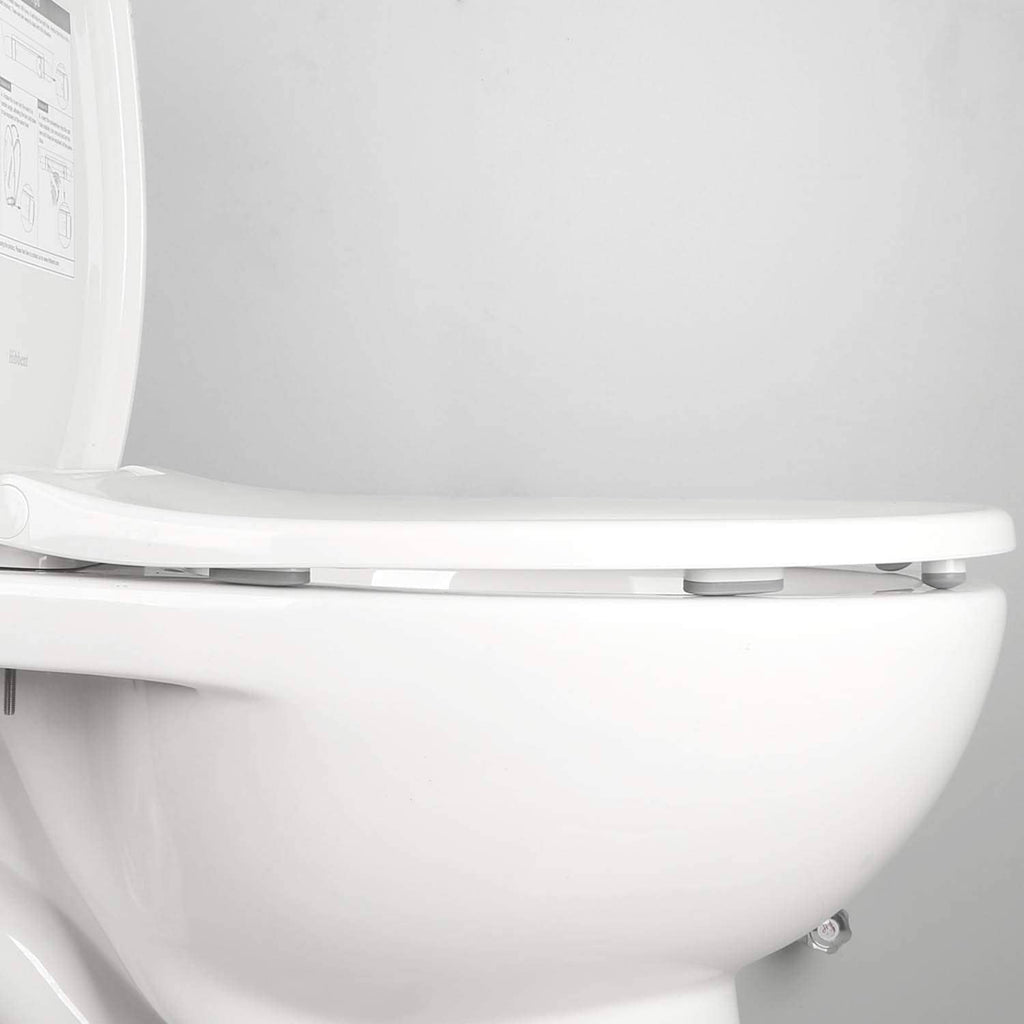 Close-up of gray toilet seat bumper pads under the lid on a white toilet seat
