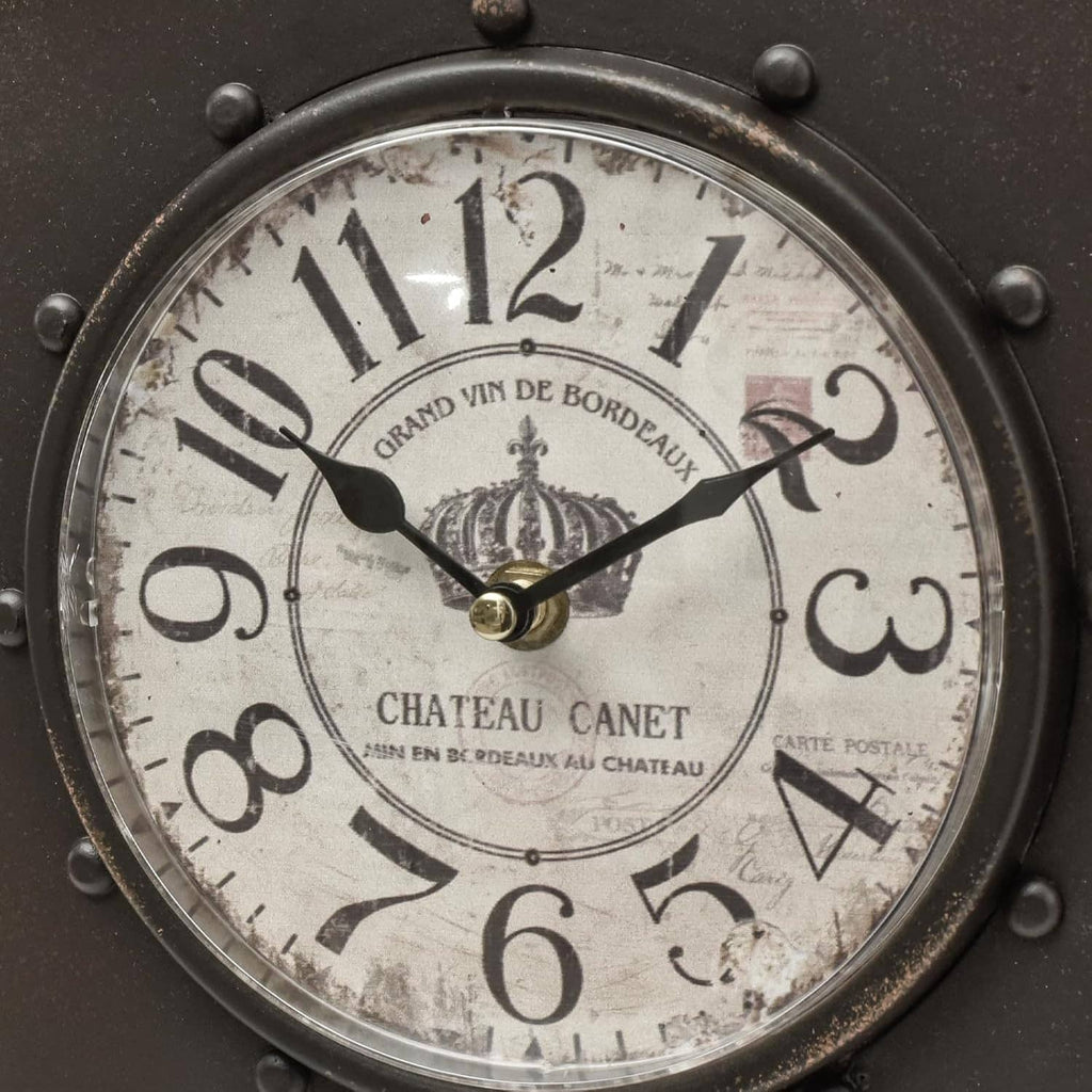 Close-up of dark wall clock face with Roman numerals and decorative hands