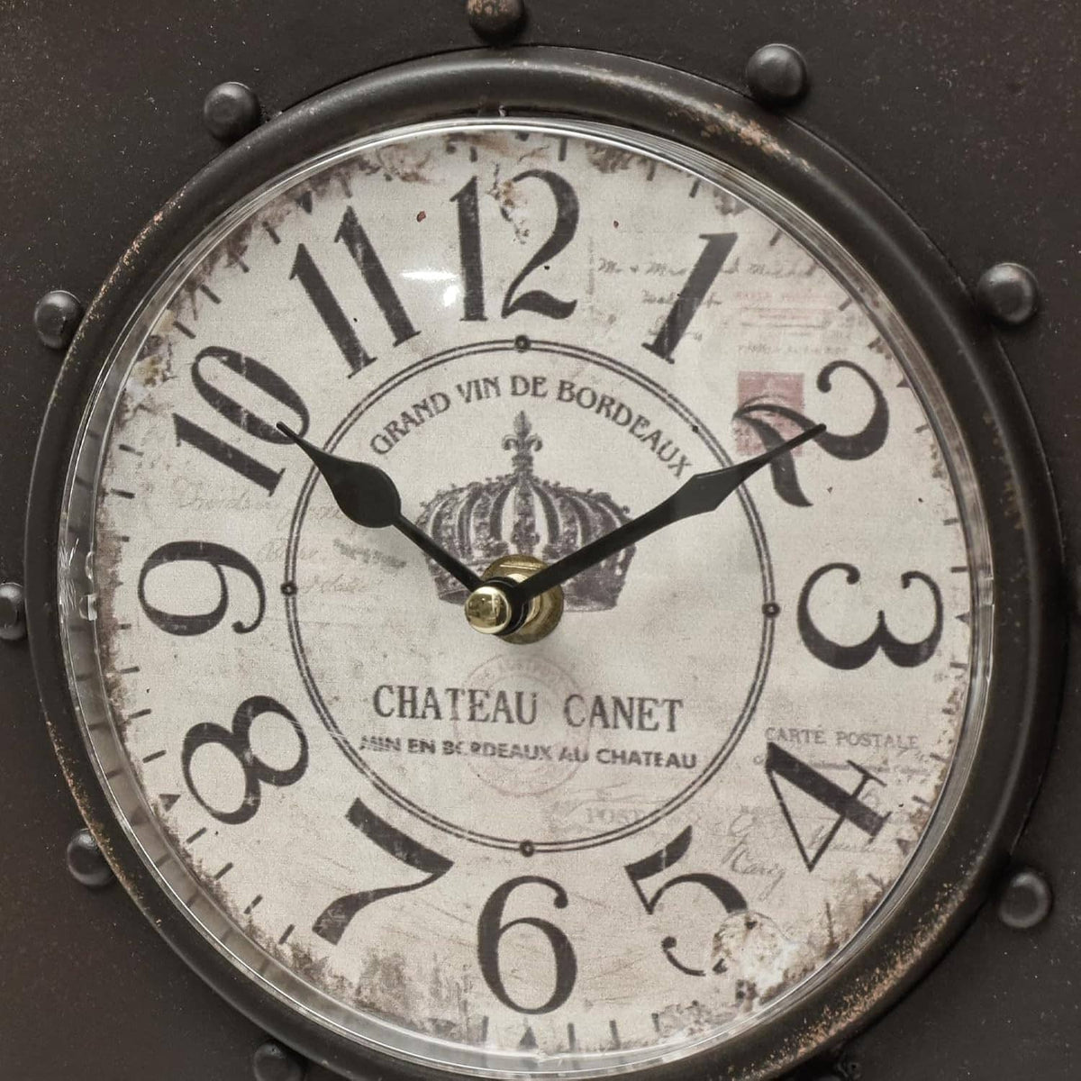 Close-up of dark wall clock face with Roman numerals and decorative hands