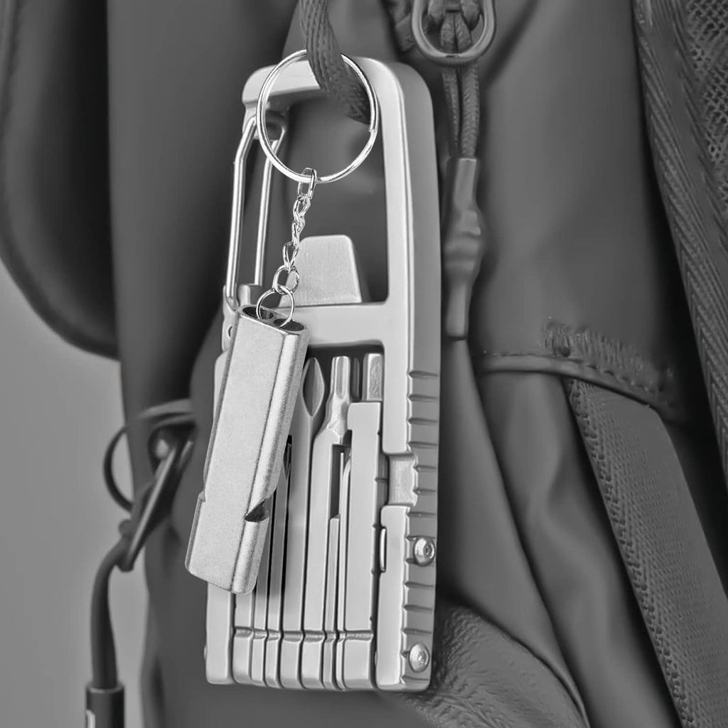 Stainless steel mini multi-tool keychain hanging from a bag with visible bit compartments