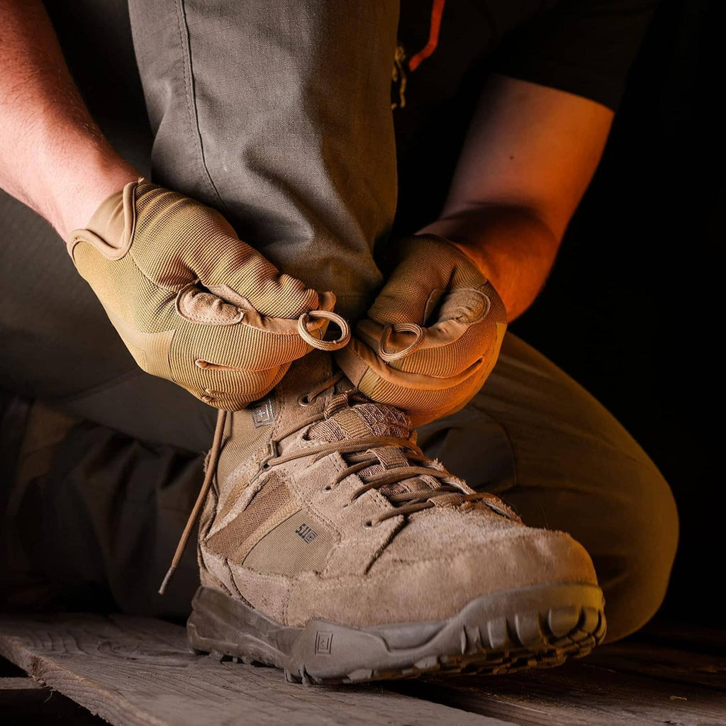 Beige touchscreen sport gloves with elastic cuffs, worn while tying shoes.