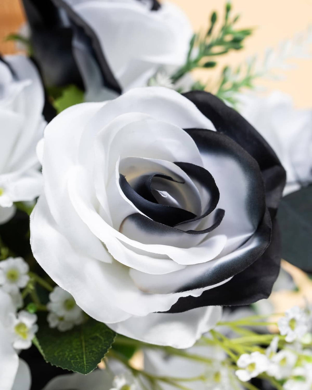 Close-up artificial silk rose with white petals, dark center, and green leaf