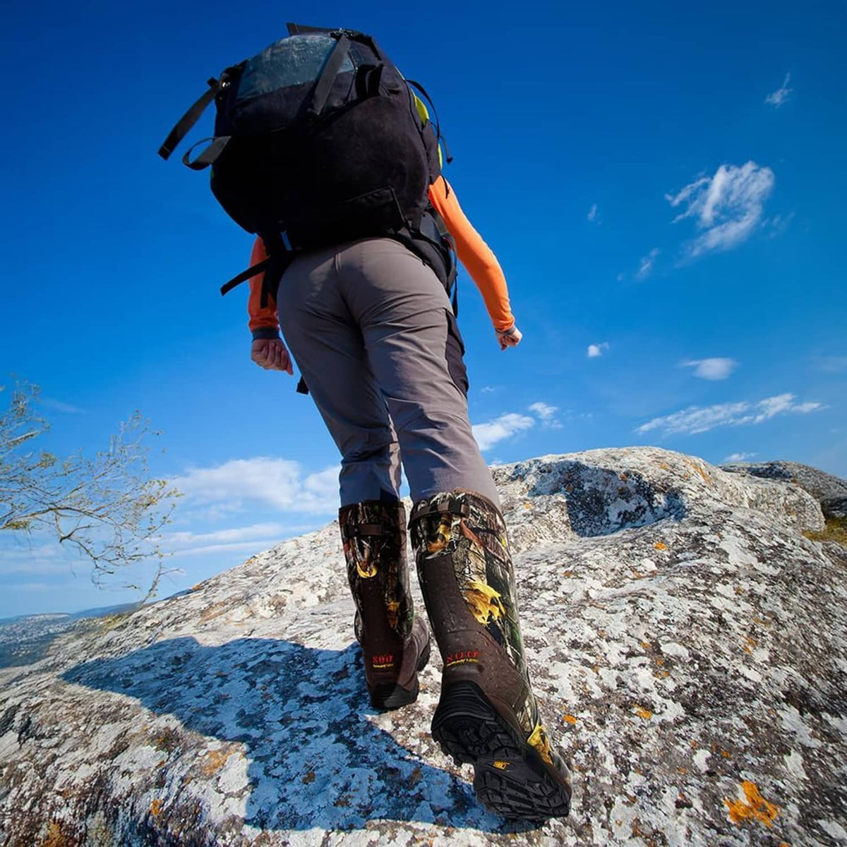 Camo hunting boots on rocky terrain, rugged outsole tread and tall shaft.
