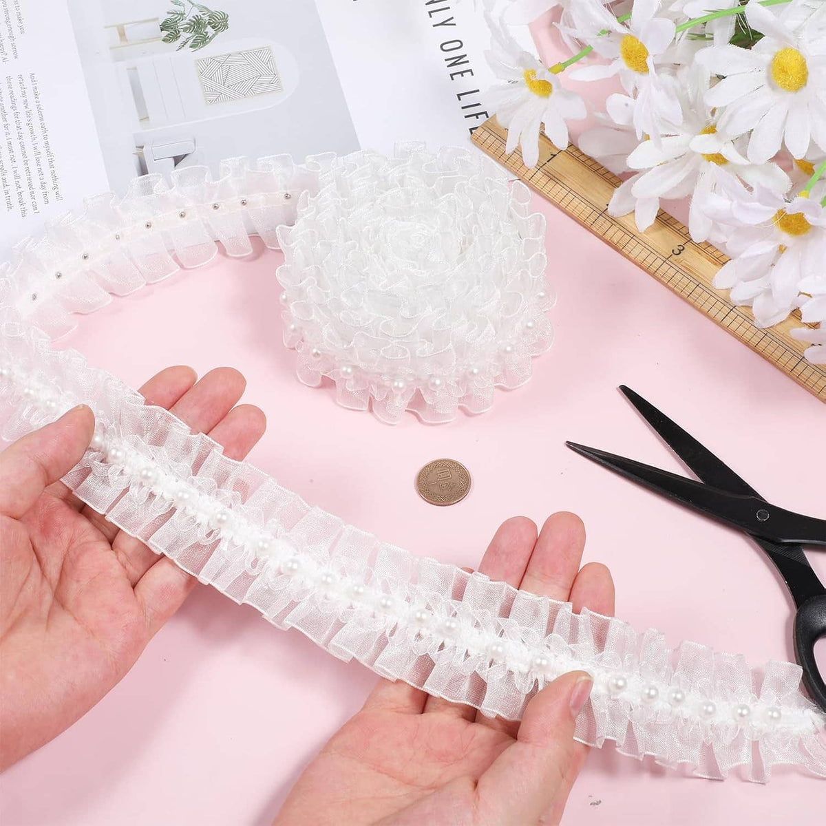 White pearl ruffle lace trim strip held in hand, featuring bead accents along edge